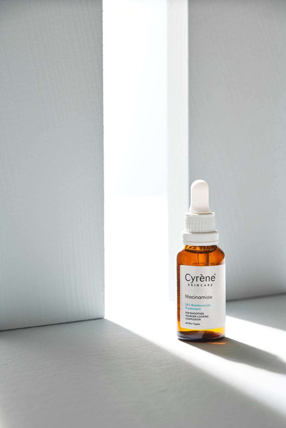 Cyrène Niacinamide serum in natural light with architectural shadows
