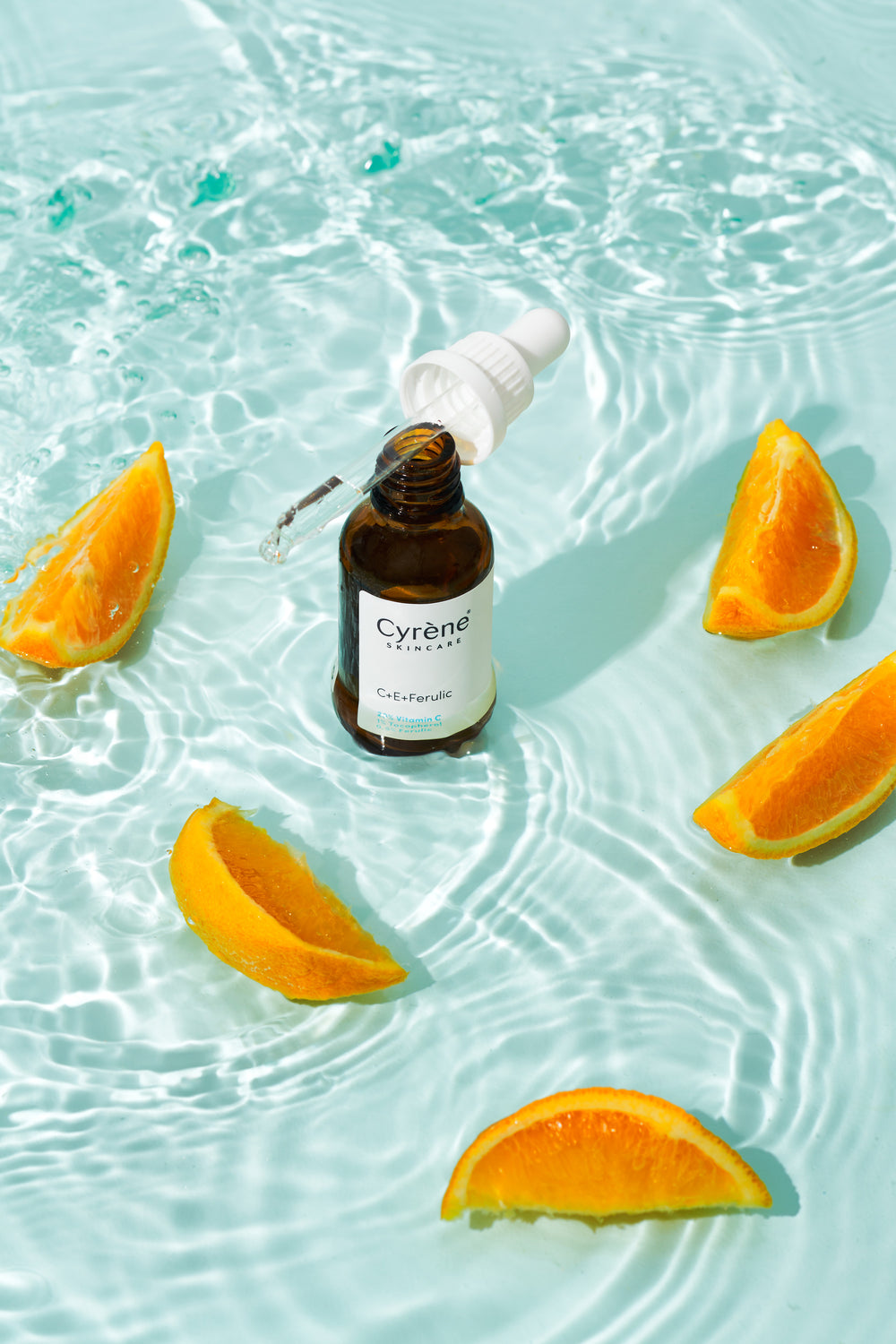 Cyrène C E Ferulic serum photographed with orange slices and rippling water
